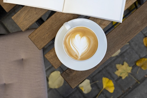 写真 秋の朝、ストリート カフェで一杯のコーヒーと本