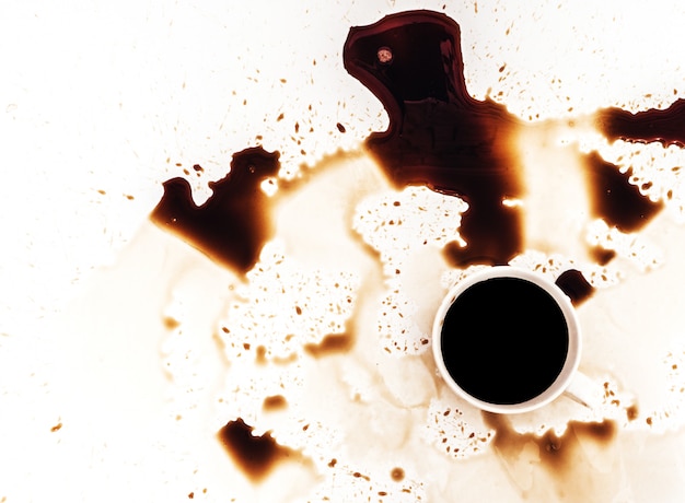 Фото Чашка кофе разлила на белой предпосылке, взгляд сверху. для гранж рекламы, скопируйте пространство