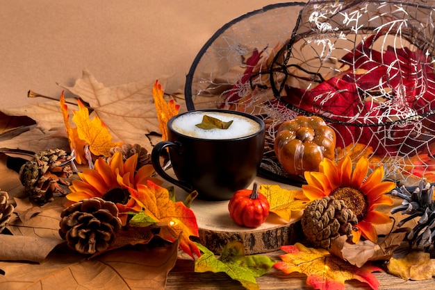 Фото Чашка кофе с листьями шляпы ведьмы и тыквой осень и хэллоуин фон сверху