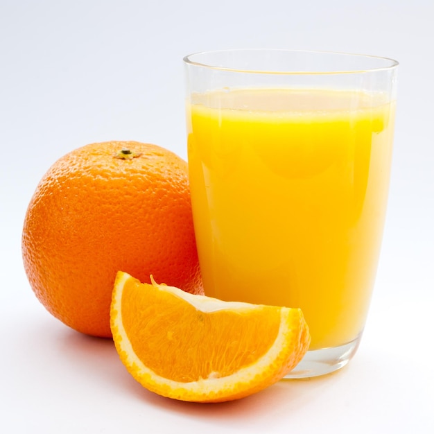 A cup of orange juice and fresh orange