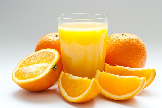 A cup of orange juice and fresh orange