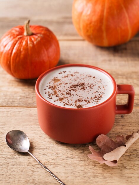 Cup of pumpkin latte on wooden background, autumn fall mood