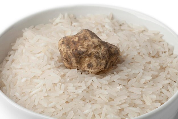 Cup of raw rice with fresh white truffle on white background close up
