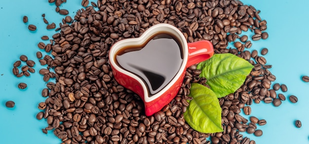 Cup in the shape of a heart with coffee and coffee beans