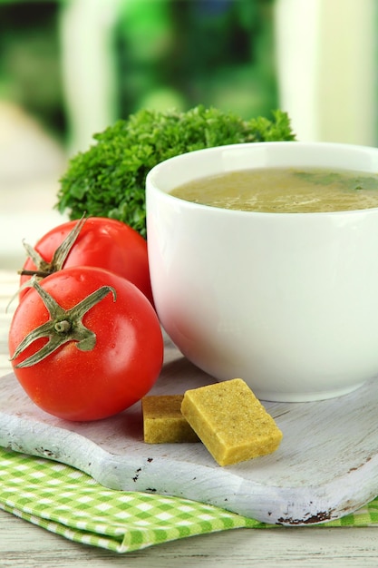 Cup of soup with bouillon cubes on wooden table