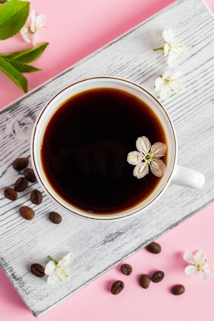 ピンクの背景に濃いエスプレッソコーヒーと繊細な春の花のカップ春