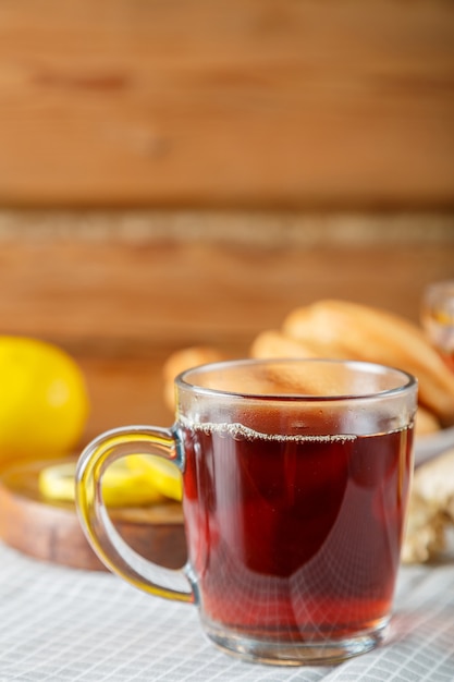 A cup of strong infused tea on a napkin next to lemon ginger.