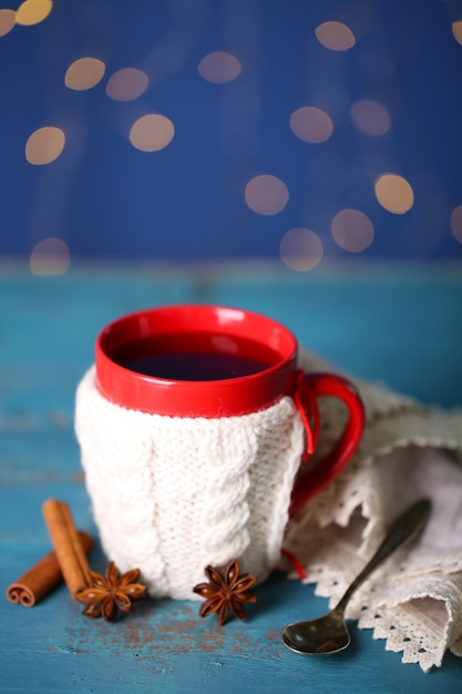 Cup of tasty hot tea on wooden table on shiny background