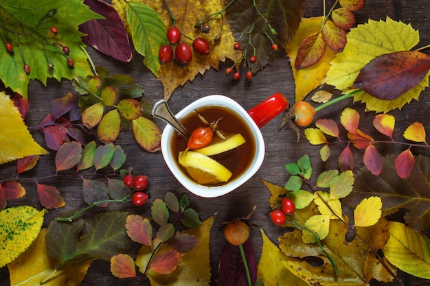 木の表面に色とりどりの紅葉を背景にお茶を一杯