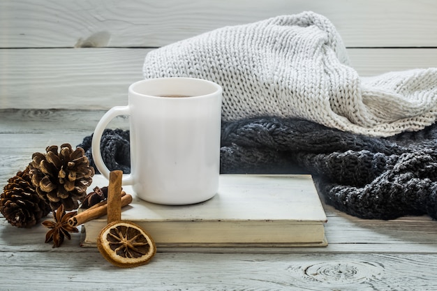 Cup of tea on a beautiful wooden table with winter sweater, old book