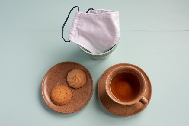 Cup of tea biscuits and diy face mask on plain desk