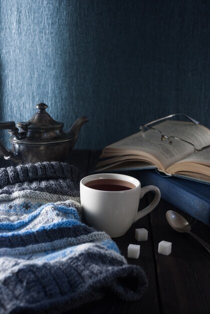 Cup of tea, book and knit cap on a wooden table