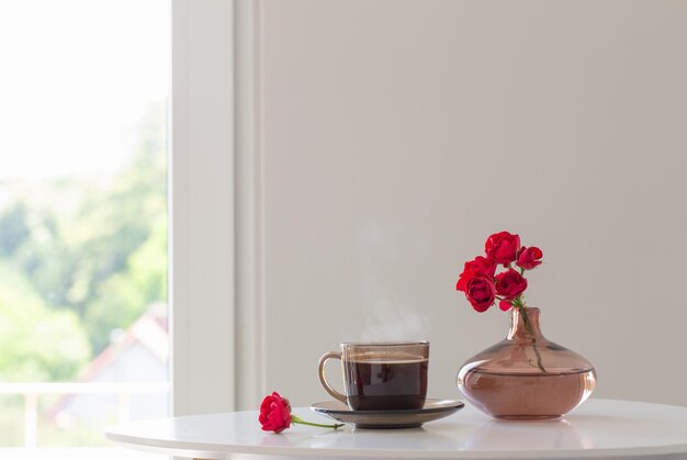 Cup of tea and bouquet of roses in white interior