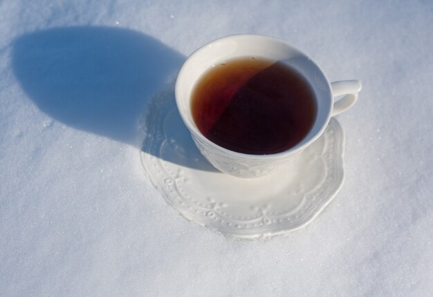 Cup of tea for breakfast on snow background outside