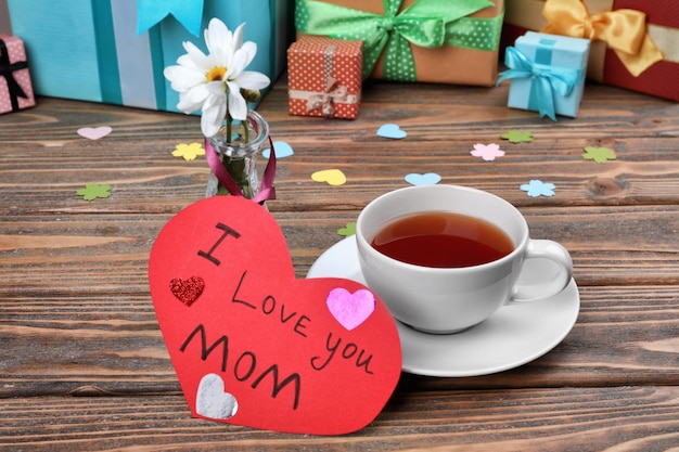 Cup of tea and card with words I love you Mom on table Mother's Day celebration