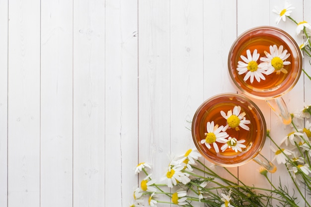 Cup of tea and chamomile flowers on wooden background