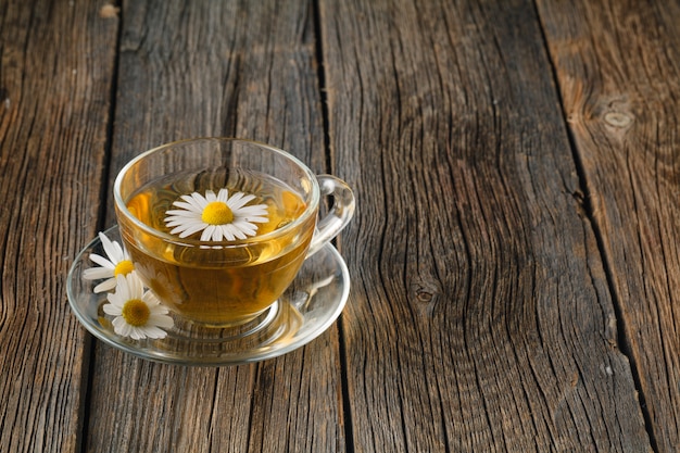 Cup of tea and chamomiles on wooden surface