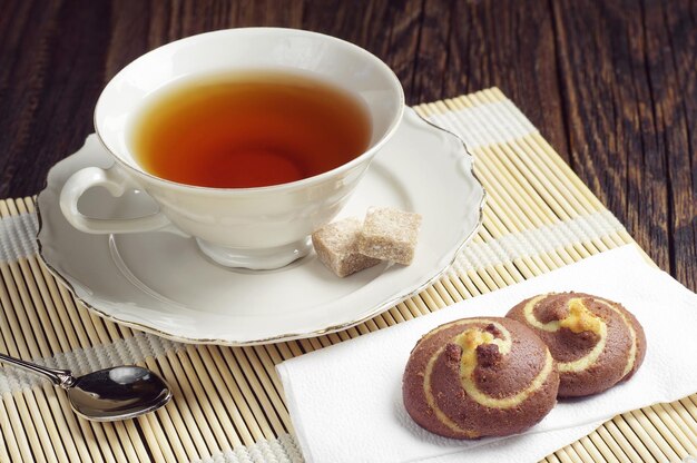 Cup of tea and chocolate cookies on bamboo napkin