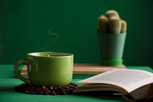 cup of tea or coffee green color hot with steam open book cactus with table and green