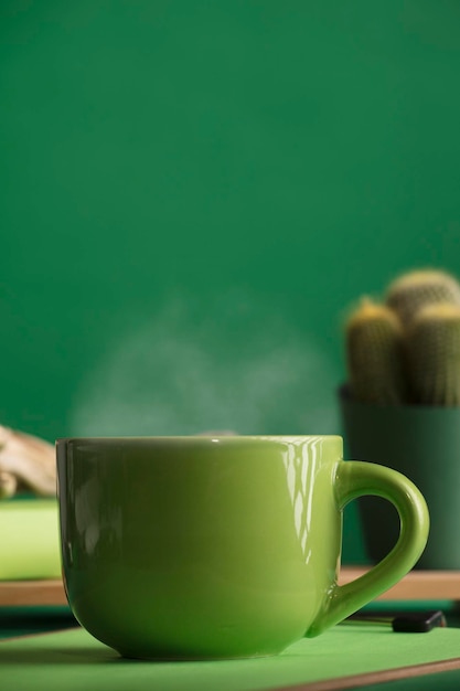 Cup of tea or coffee green color hot with steam space for text green background