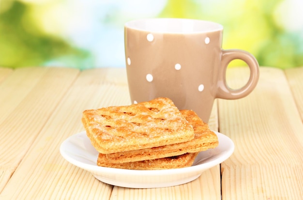 Cup of tea and cookies on wooden table on bright background