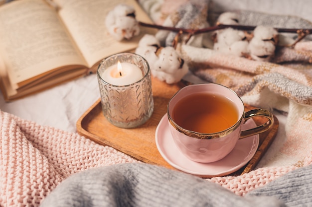 Cup of tea, cotton, cozy, book, candle. Cosy autumn winter concept.