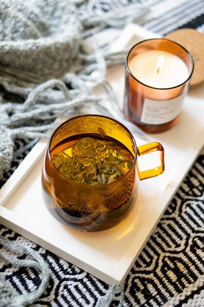 Cup of tea and cozy burning candle on white tray