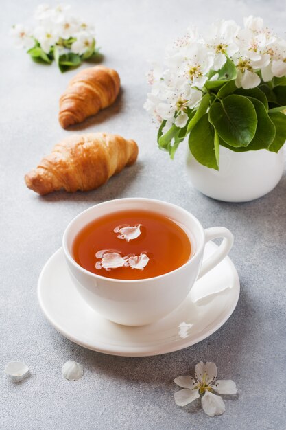 Cup of tea and croissant on gray 