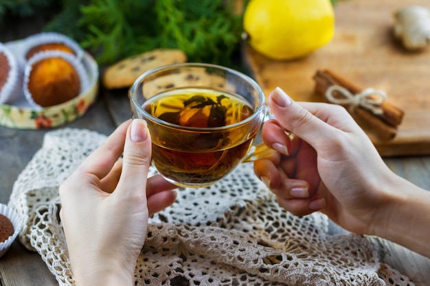 クリスマス クッキーとテーブルの上のレモンと女性の手でお茶のカップ