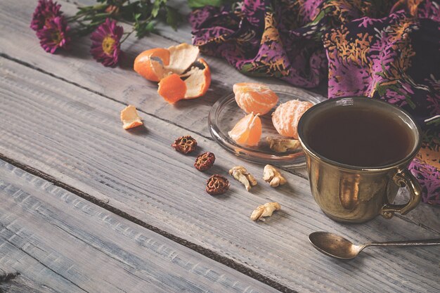 Чашка чая, цветов и мандарина на белом деревянном столе