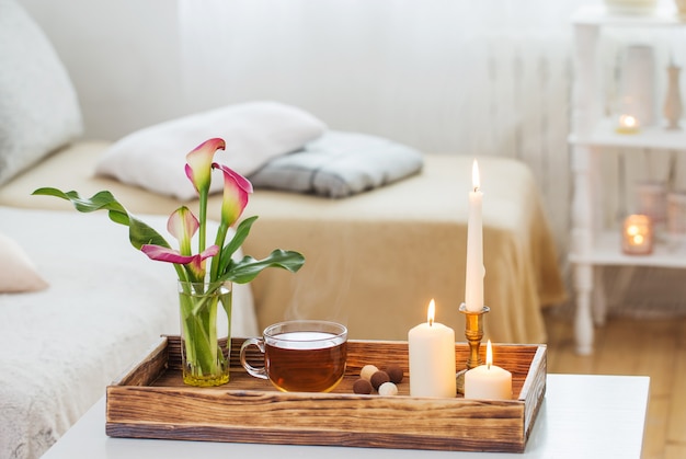 Cup of tea and flowers on wooden tray indoor