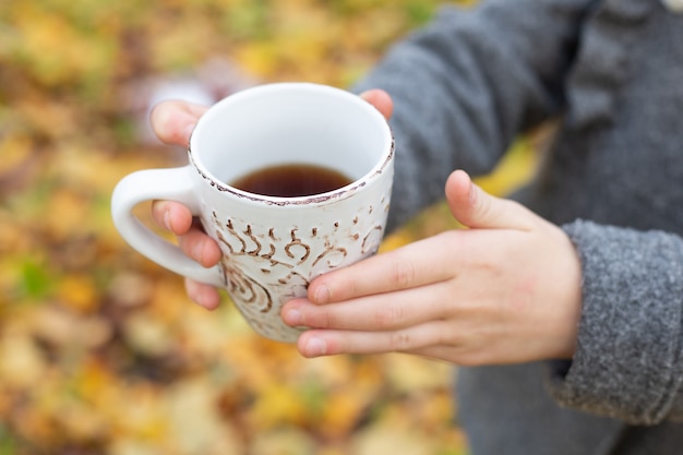 屋外で手にお茶を一杯。秋の森の中を歩く-画像