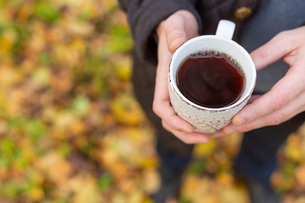 Tazza di tè in mano all'aperto. passeggiata nella foresta autunnale - image