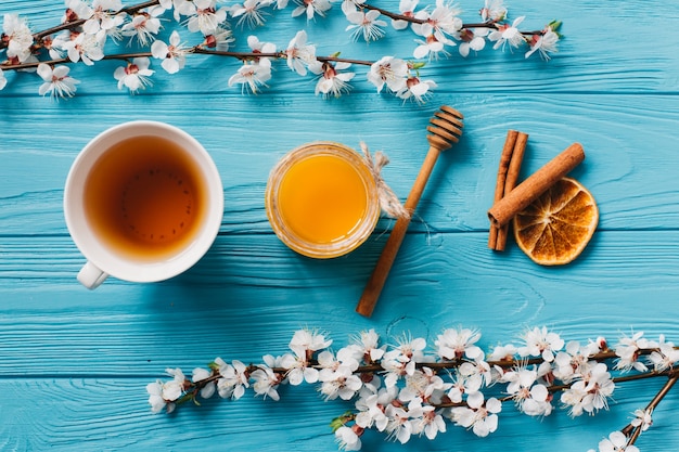 青い木製の背景にお茶と蜂蜜のカップ