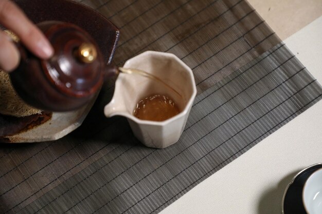 A cup of tea is filled with a brown liquid.