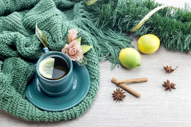 A cup of tea on a knit winter scarf closeup on a wooden table