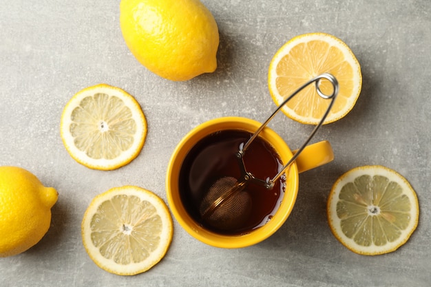 Cup of tea and lemons on grey, top view