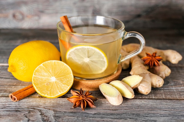 Foto tazza di tè a base di radice di zenzero fresco, limone e spezie di cannella e anice su uno sfondo di legno. ingredienti naturali antiinfluenzali organici, medicina alternativa, supporto immunitario. bevanda tonica energetica.