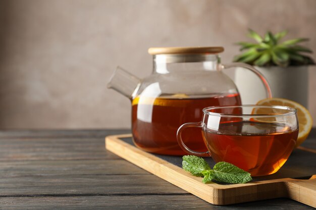 Cup of tea, mint, honey, ginger and teapot on wooden, space for text