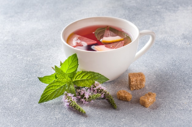 Cup of tea, mint and lemon on grey table