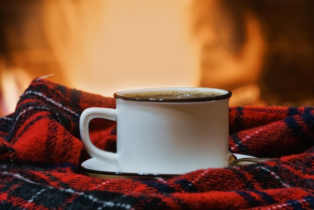 Photo a cup of tea near a cozy fireplace in a country house winter or autumn holidays