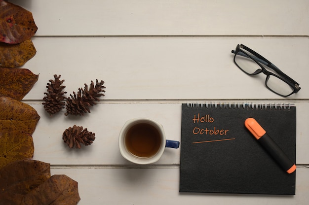 Cup of tea note with words hello October and eyeglasses on a wooden background Autumn concept