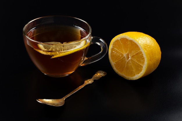 Cup of tea and pieces of lemon on black background