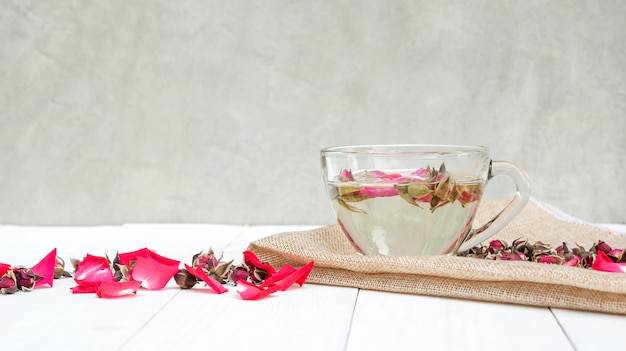 A cup of tea pink rose on a white wooden table.