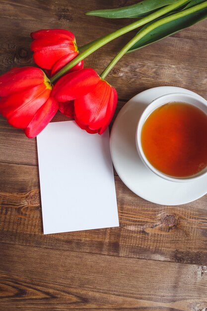 A cup of tea red tulips pattern on wooden table