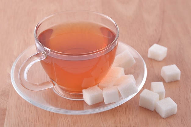 Photo cup of tea and refined sugar on a  wooden  background