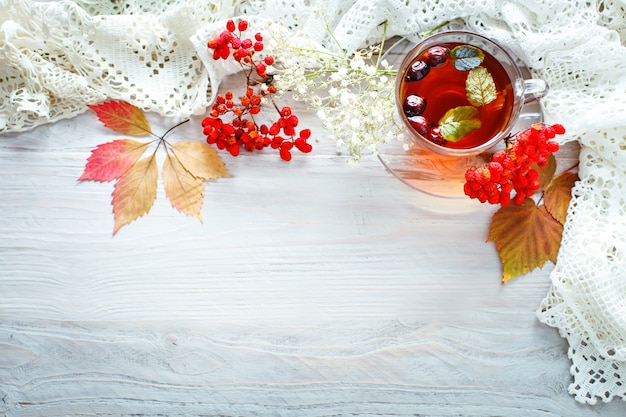 A Cup of tea and Rowan berries on a wooden table. Autumn still-life.