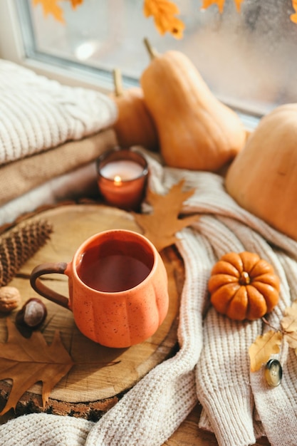 Una tazza di tè a forma di zucca e decorazioni autunnali sulla foto estetica del davanzale