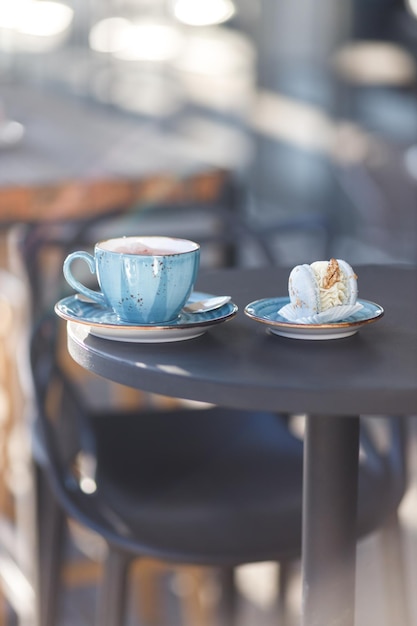 お茶のカップが木製のテーブルの上に立っています カップはお茶で満たされています マカロンのカップの右側に 秋のテーマの木製の背景