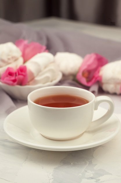 Чашка чая, сладости и розовые цветы